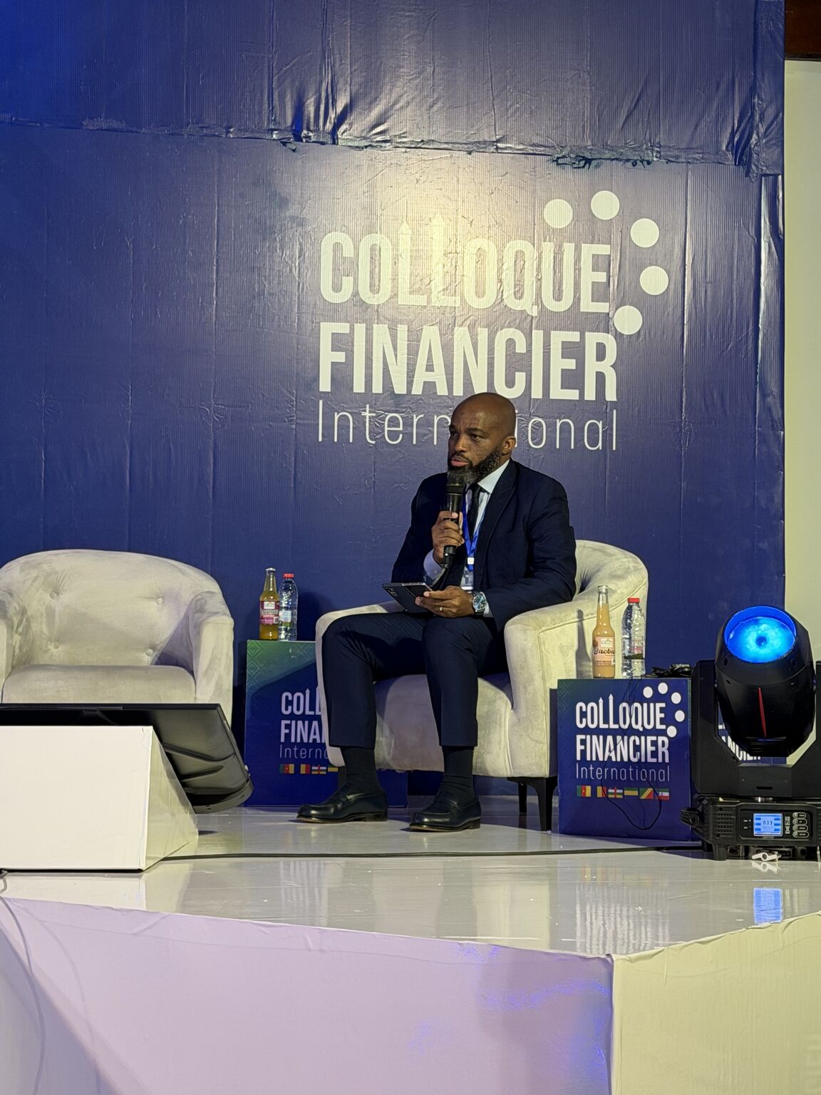 Stéphane DEFO speaking with a microphone during COLFINI 2026 in Yaoundé.
